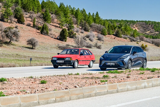 A red Lada Samara classic car and a gray MG4 Electric drive side by side on a country road in Anatolia, symbolizing generational change and modern automotive development in Turkey's road traffic 02.04