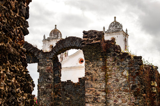 Facade and towers of an old Baroque church seen through the stone ruins of the town of Alcantara, Maranhao.