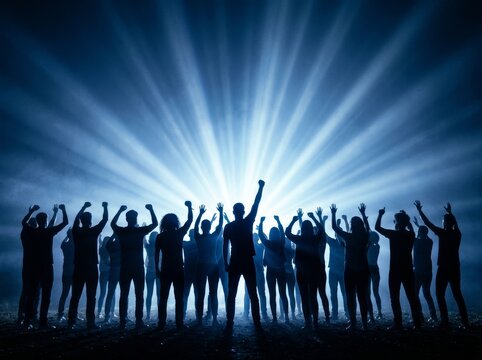 A group of people with raised arms celebrates in blue light. Silhouette creates dramatic effect.