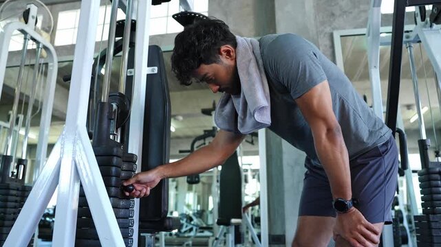 Dedicated male athlete fine tuning weights on gym equipment to enhance strength and improve fitness levels