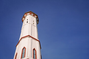 Obraz premium Low angle view of a tall white architectural tower with red trim standing against a clear bright blue sky with negative space for copy space.