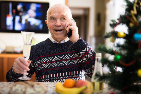 Happy elderly man talking on phone at table during Christmas celebration