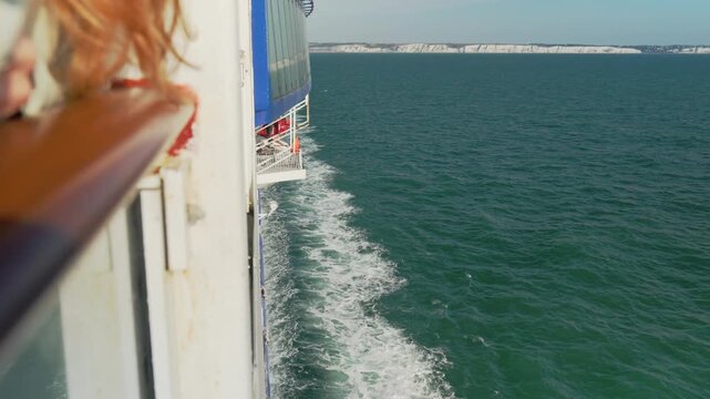 Red Haired Woman Leaning on Ferry Railing with White Cliffs of Dover
