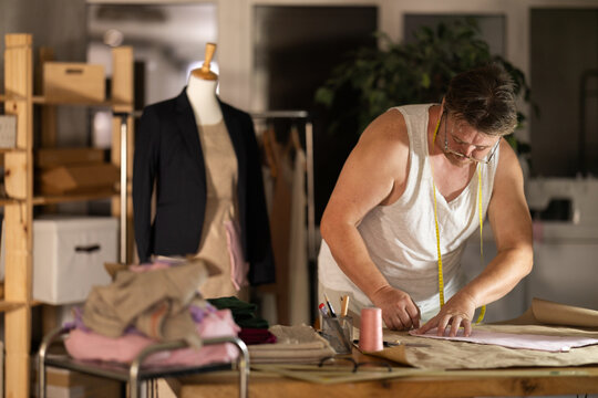 Man tailor creates dress pattern, traces detail of product on paper