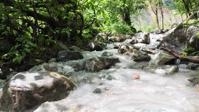 Glacial meltwater stream rushing over wet rocks below Shkhara glacier in Mestia, Svaneti region of Georgia, pristine mountain wilderness and wild nature conservation concepts