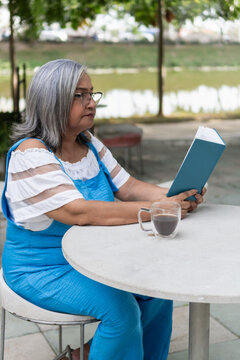 Senior woman reading book enjoying outdoor cafe