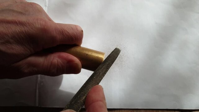 Metal filing close up processing steel surface with hand file creating metal crumbs and shavings in 4K Ultra HD footage.
