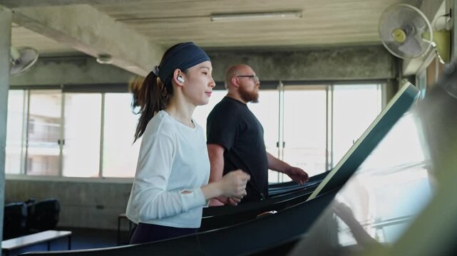 Energetic couple exercising side by side on treadmills in a contemporary fitness center