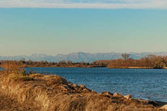 vista che si estende dalle sponde della foce del fiume Isonzo verso le alte catene montuose delle Alpi della regione Friuli Venezia Giulia, di pomeriggio, in inverno
