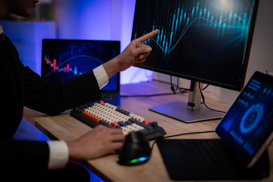 Asian Businessman Trading Stocks and Analyzing Financial Data Charts on Multiple Screens in Dark Office at Night