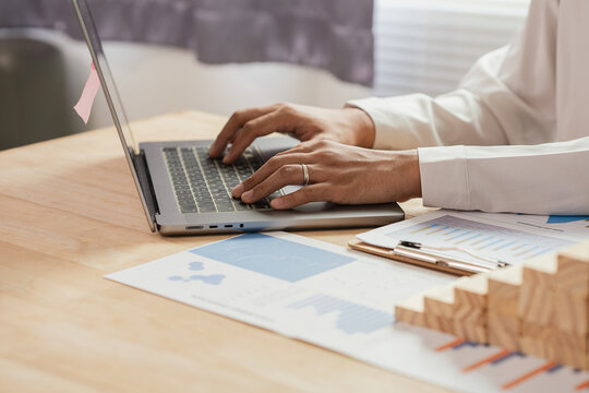 Businessman Using Calculator to Calculate Financial Growth, Investment Strategy and Mortgage Planning with Wooden Block House Stairs