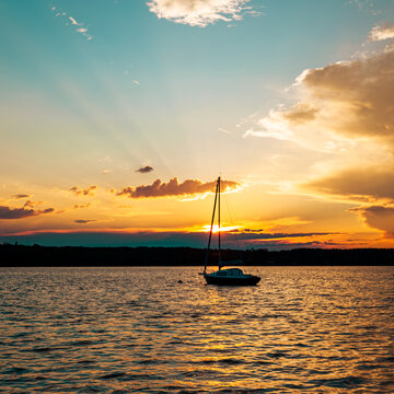 landscape of a peaceful sunset over W&ouml;rthsee lake, near Ammersee in Bavaria, Germany, Europe. Dramatics clouds, Dark, heavy storm clouds gather. Radiant golden sunbeams burst through in the cloud