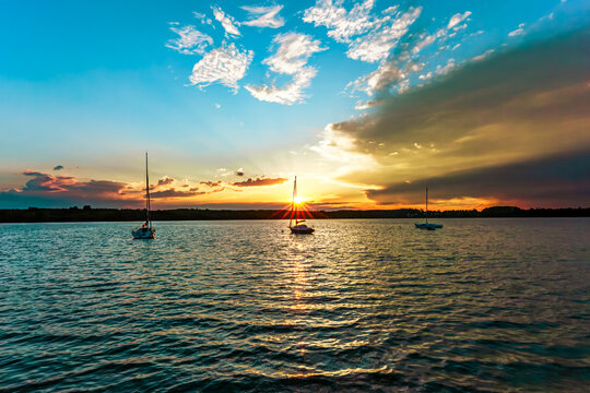 landscape of a peaceful sunset over W&ouml;rthsee lake, near Ammersee in Bavaria, Germany, Europe. Dramatics clouds, Dark, heavy storm clouds gather. Radiant golden sunbeams burst through in the cloud