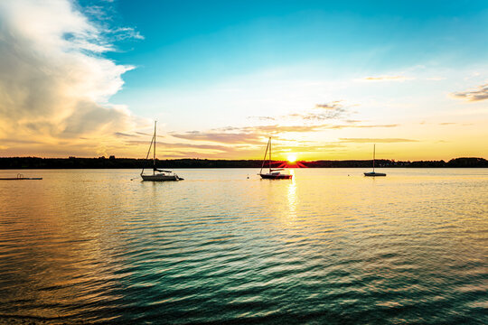 landscape of a peaceful sunset over W&ouml;rthsee lake, near Ammersee in Bavaria, Germany, Europe. Dramatics clouds, Dark, heavy storm clouds gather. Radiant golden sunbeams burst through in the cloud