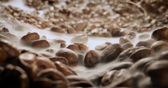 Steaming roasted coffee beans background with selective focus.