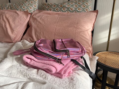 Baby backpack with folded clothes in bed close up