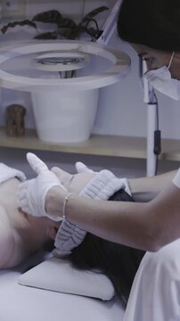 Gloved hands performing a facial skincare treatment under ring light
