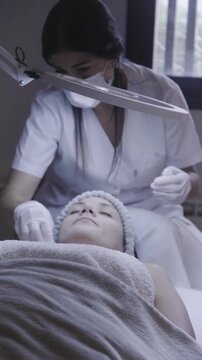 Esthetician performing precise facial skincare procedure under studio light