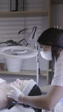Focused hands applying gentle facial care beneath a ring light