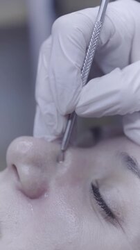 Precise metal tool gliding along closed eye during facial treatment