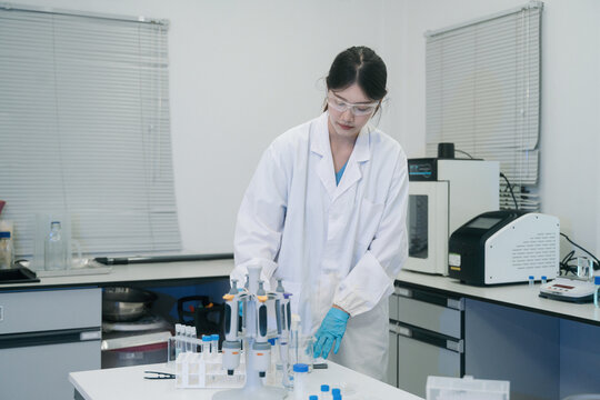 Young Asian Female Scientist Working in Modern Laboratory with Pipettes and Test Tubes