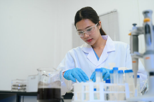 Asian Female Scientist Working with Test Tubes in Modern Laboratory Research Facility