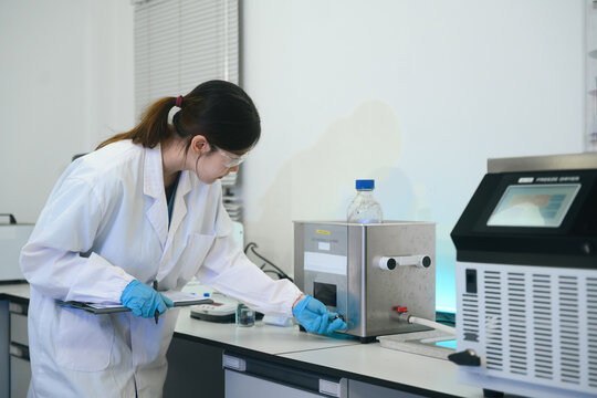 Female Scientist Operating Ultrasonic Cleaner in Modern Laboratory with Safety Equipment