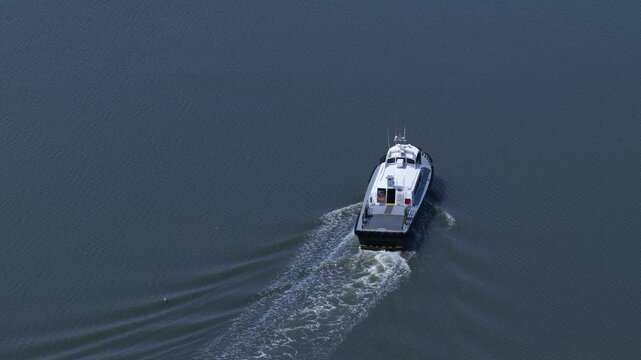 Boat motoring on Cedar Creek on Delaware coastline on peaceful summer day with sunshine and cloud shadows