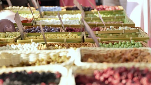 Hand scooping roasted peanuts at a street market food stall with various snacks
