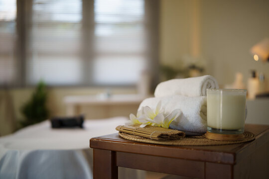 Massage treatment room prepared with towels, a candle, and spa products.
