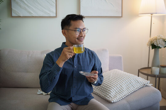 Asian man enjoying tea during a relaxing break at home.