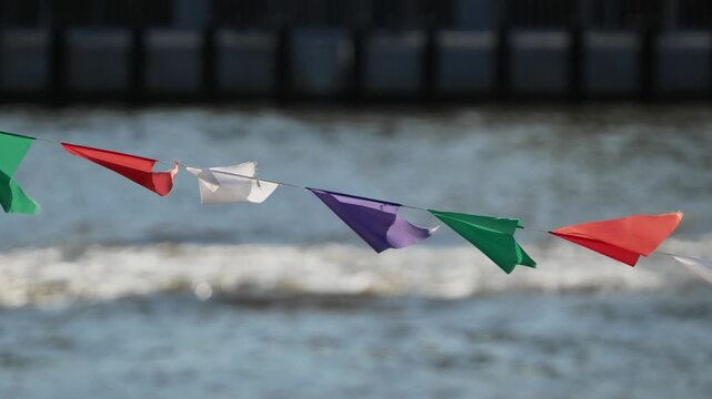Colorful bunting flags fluttering over water during an outdoor celebration event