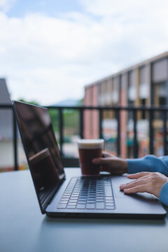Vertical closeup image of a woman working and touching on laptop computer touchpad while drinking coffee in cafe