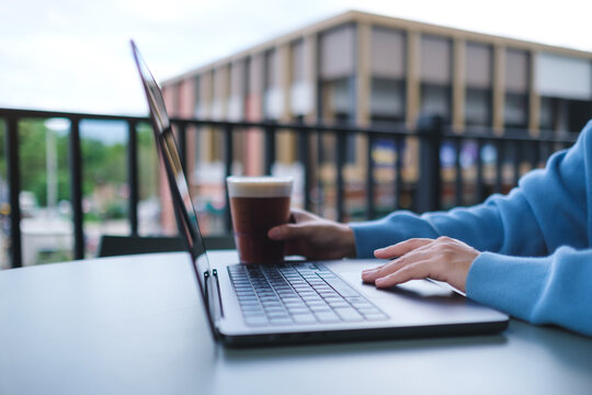 Closeup image of a woman working and touching on laptop computer touchpad while drinking coffee in cafe