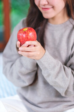 Vertical closeup image of a woman holding a red apple