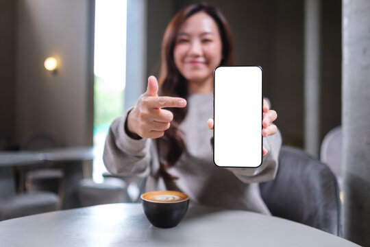 Mockup image of a woman holding and pointing finger at a mobile phone with blank white screen