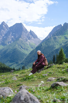 Vertical portrait image of a woman sitting on a yard with mountain range in summertime, Chengdu, China