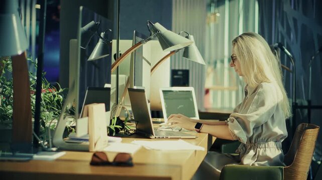 Employee Typing On Laptop Keyboard While Sitting At Desk With Computer Monitors In Modern Office 