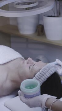 Careful brush application soothes closed eyes in calm facial treatment