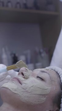 Soft brush glides across cheek during calm clay mask facial