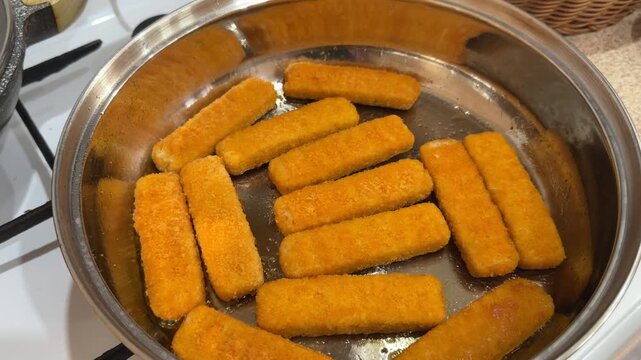 Fish sticks frying in pan macro closeup