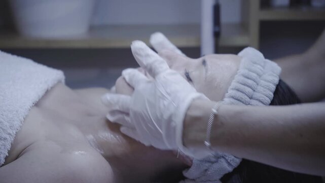 Gloved hands applying gentle facial massage during skincare session