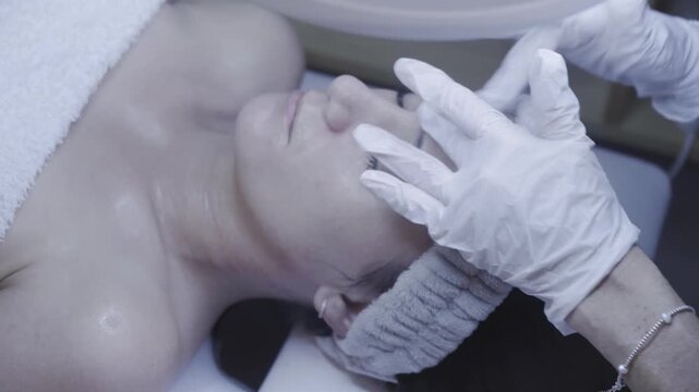 Gloved fingers gently sculpting the face in a calming facial massage