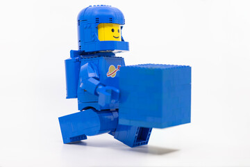 Fototapeta premium Hong Kong, June 8, 2026: A classic blue LEGO spaceman carries a blue brick block, symbolizing a playful gift of building element.