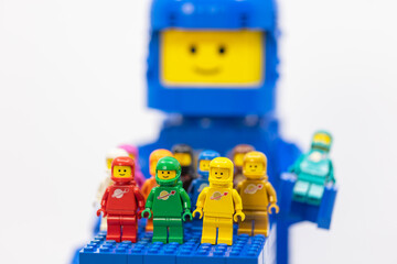 Fototapeta premium Hong Kong, June 8, 2026: Colorful classic spacemen gather on a blue baseplate before a giant smiling LEGO head.