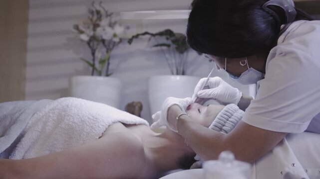 Focused esthetician performing precise facial skin treatment
