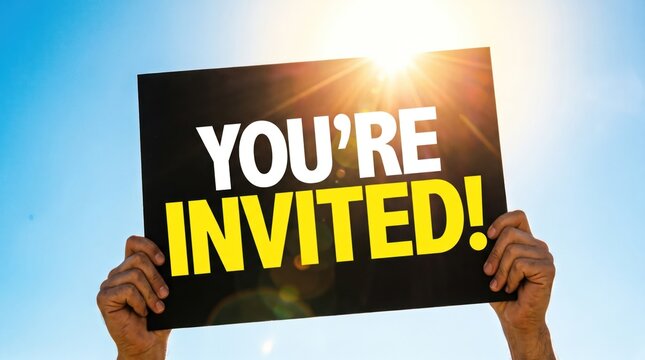 Hands holding a sign reading &ldquo;You&rsquo;re invited&rdquo; against a bright blue sky