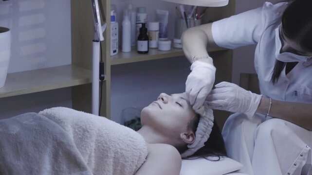 Skincare professional performing precise facial treatment under a magnifying lamp