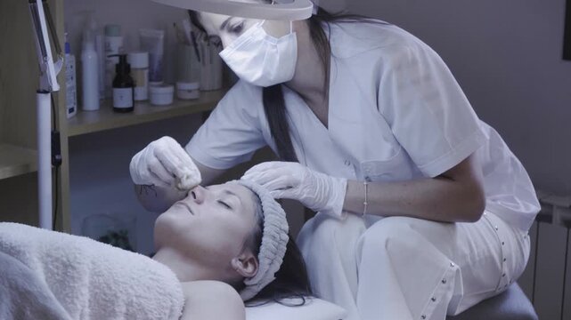 Careful skincare specialist dispensing serum drops during a facial routine