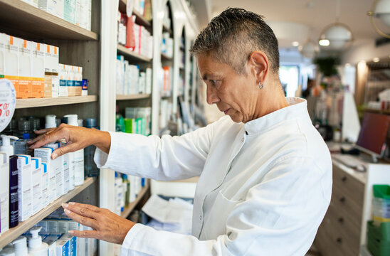 Pharmacist organizing medication on pharmacy shelves
